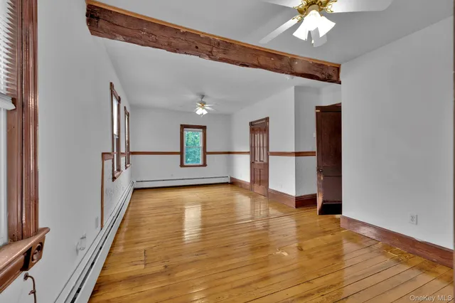 a view of a hallway with wooden floor and a kitchen