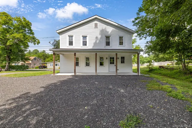 a view of a house with a yard and large tree
