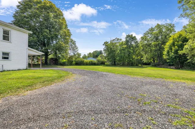 a view of a house with a big yard and large trees