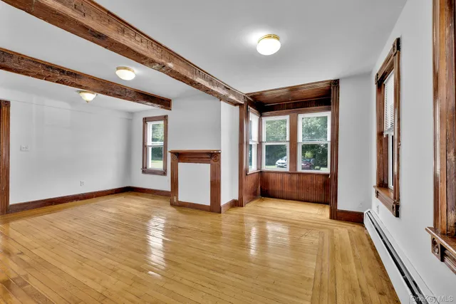 a view of an empty room with a window and wooden floor