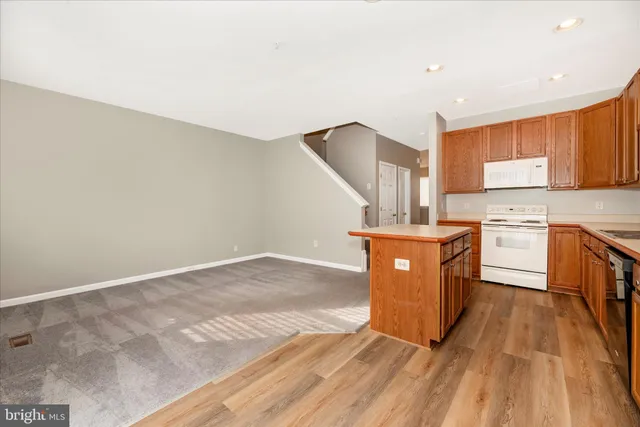 a kitchen with stainless steel appliances granite countertop a refrigerator a sink dishwasher and wooden cabinets with wooden floor