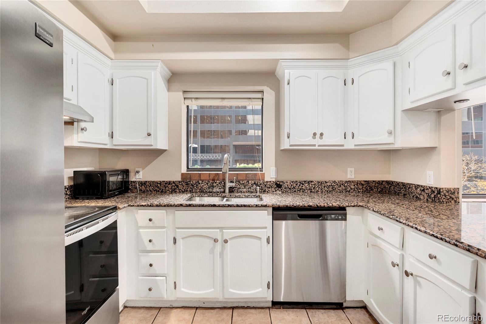1512 Larimer Street, Unit 21 Denver, CO 80202 - Photo 3 of 18 a kitchen with granite countertop white cabinets and sink