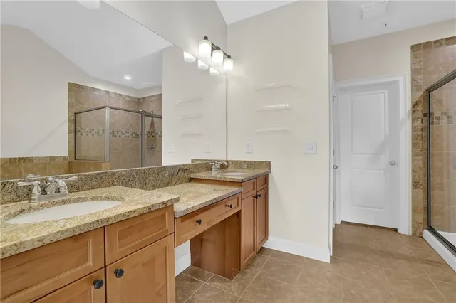 a bathroom with a granite countertop sink a large mirror and a shower