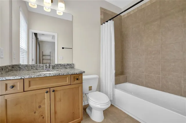 a bathroom with a granite countertop sink a toilet a mirror and bathtub