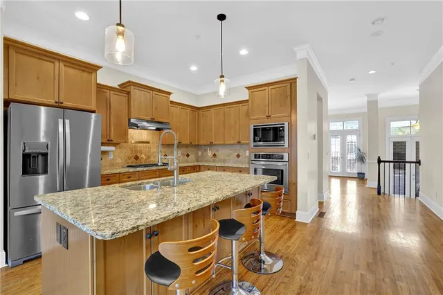 a kitchen with stainless steel appliances granite countertop a kitchen island a stove a refrigerator a oven a sink with island and chairs