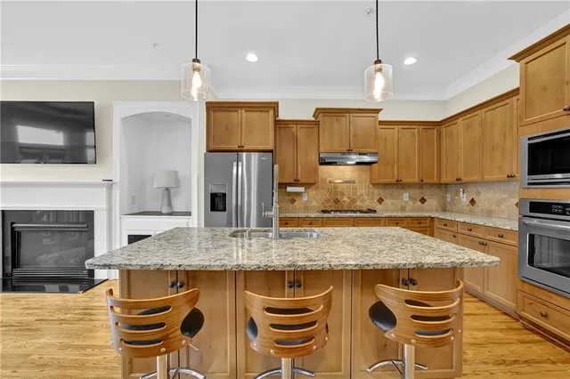 a kitchen with granite countertop kitchen island stainless steel appliances a stove sink microwave and cabinets