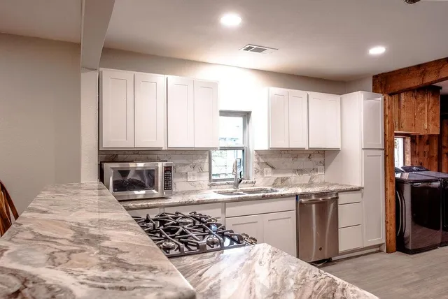 a kitchen with stainless steel appliances granite countertop a stove a sink and a refrigerator