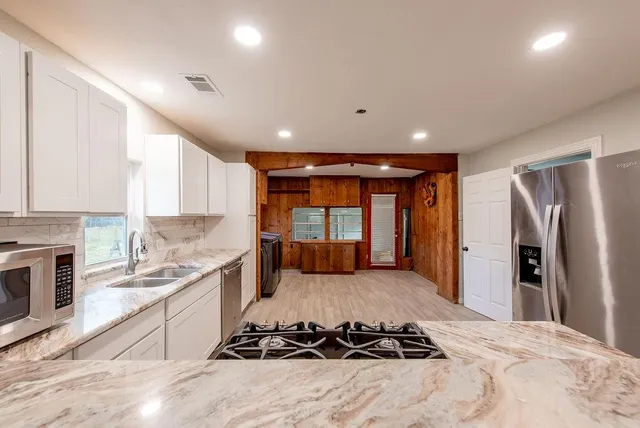 a large white kitchen with a large window and stainless steel appliances