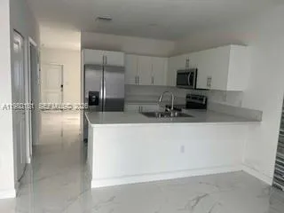 a kitchen with stainless steel appliances a refrigerator a sink a stove a microwave and cabinets