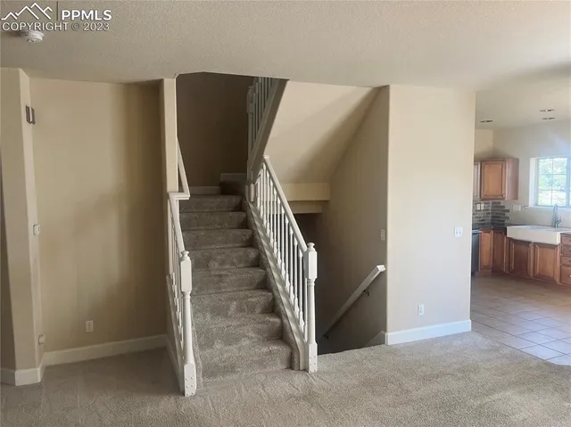 a view of a livingroom with a fireplace a chandelier and windows