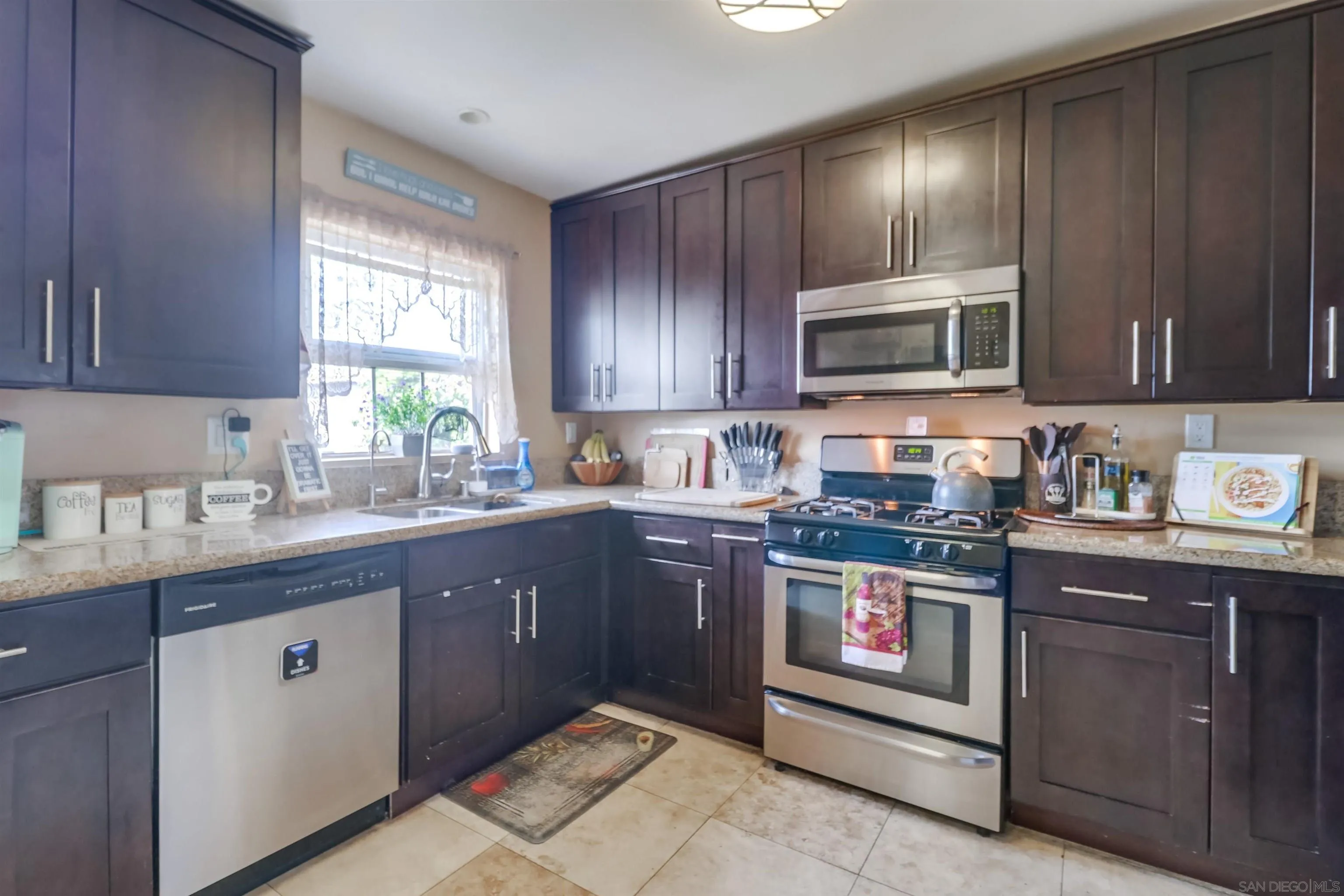 9833 St George Street Spring Valley, CA 91977 - Photo 9 of 19 a kitchen with stainless steel appliances granite countertop wooden cabinets a stove top oven a sink and dishwasher