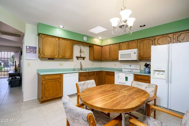 a kitchen with stainless steel appliances granite countertop a sink dishwasher a stove a refrigerator with a dining table and chairs with wooden floor