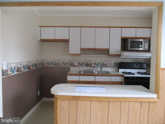 122 Hampshire Road Baltimore, MD 21221 - Photo 6 of 22 a kitchen with a sink a microwave and cabinets