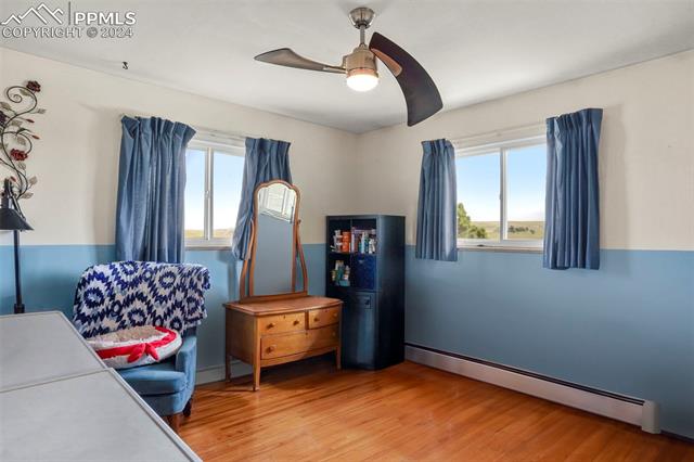 8155 Soap Weed Road Calhan, CO 80808 - Photo 16 of 39 Bedroom featuring light hardwood / wood-style floors, multiple windows, a baseboard radiator, and ceiling fan