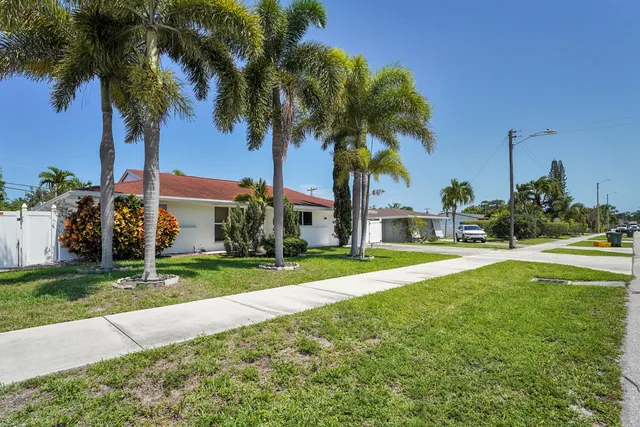 a view of a house with a yard and palm trees