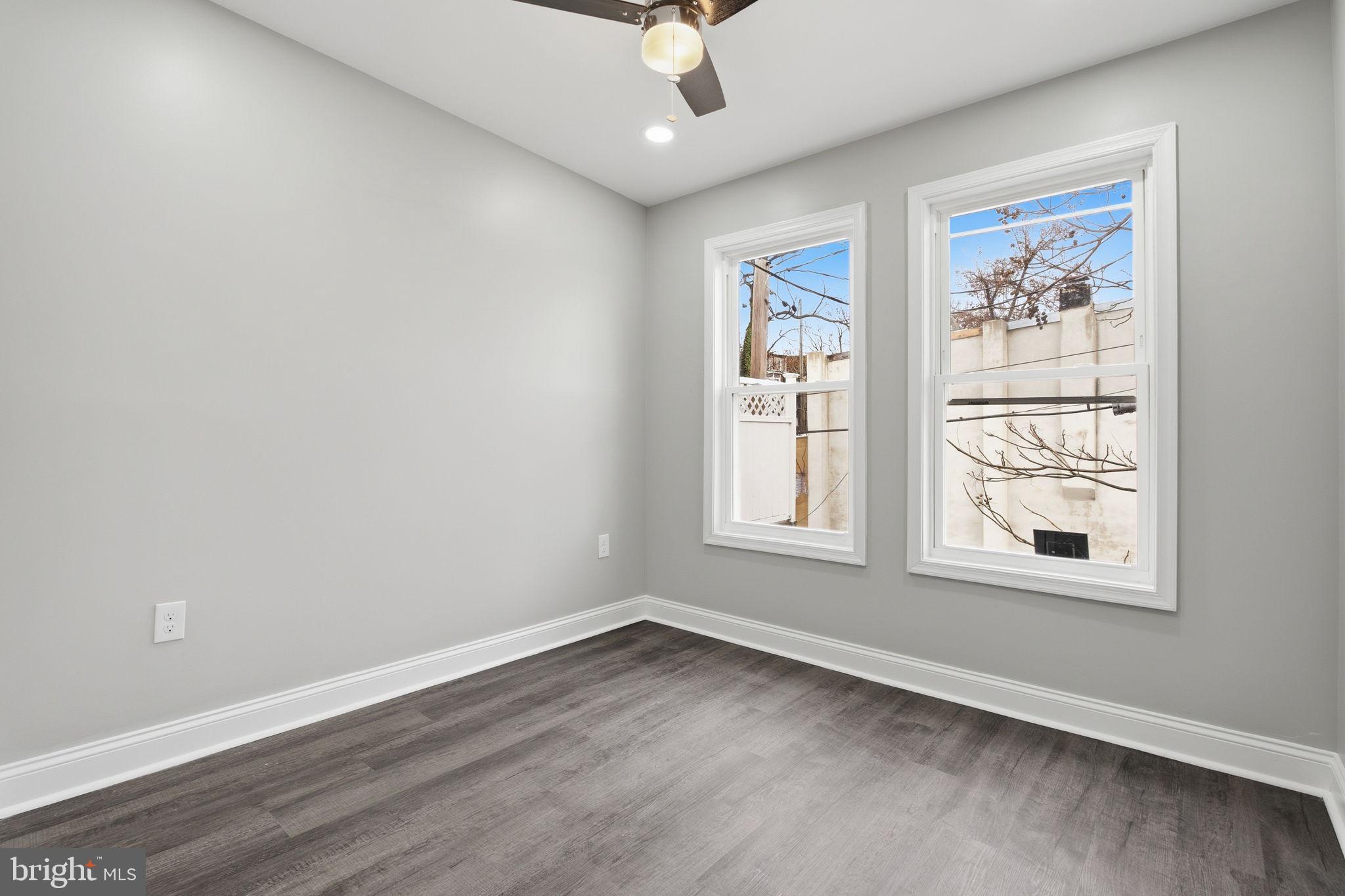 1708 Federal Street Baltimore, MD 21213 - Photo 22 of 33 an empty room with wooden floor chandelier fan and windows