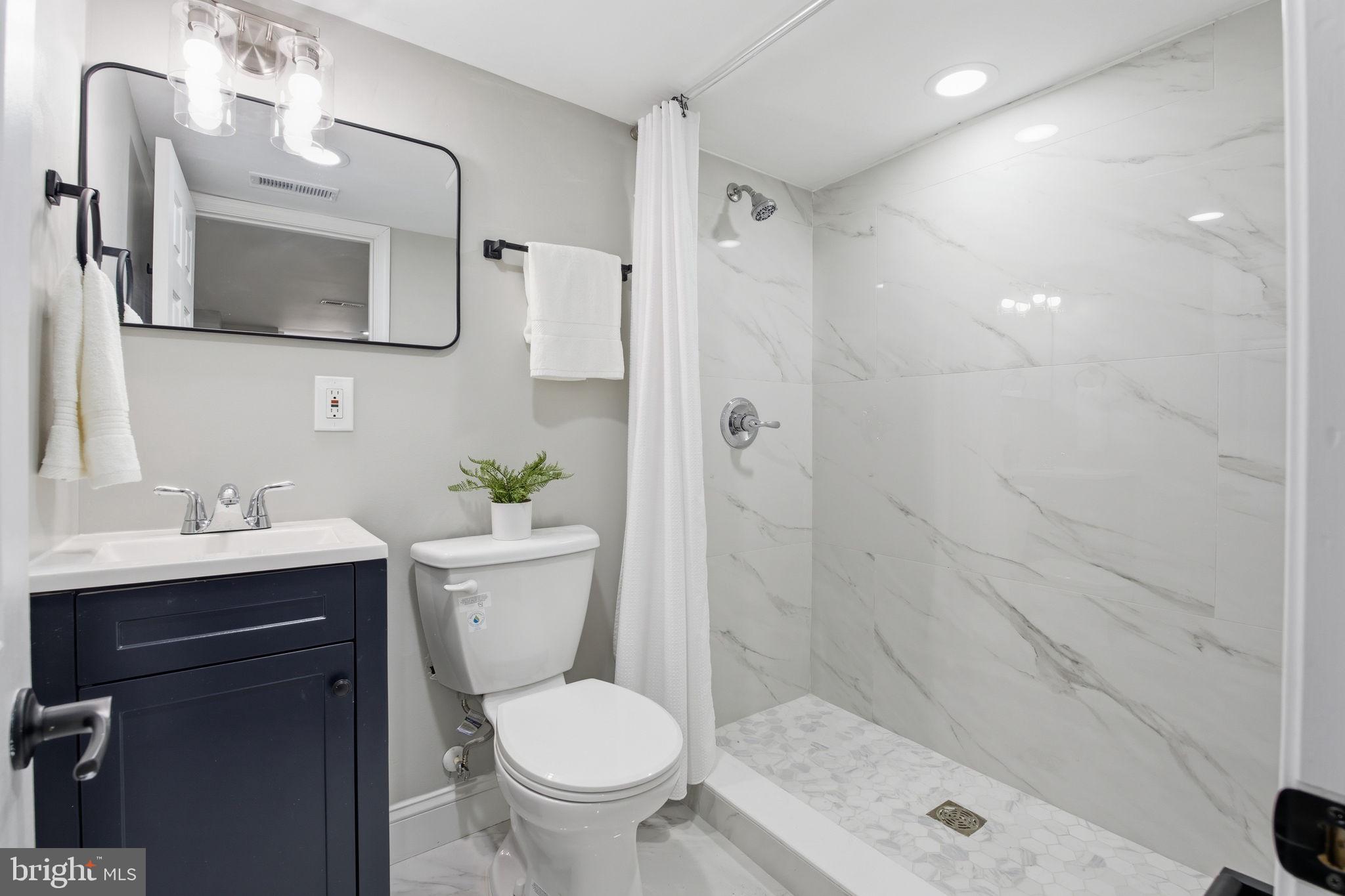 1708 Federal Street Baltimore, MD 21213 - Photo 29 of 33 a bathroom with a toilet a sink a mirror a shower and vanity