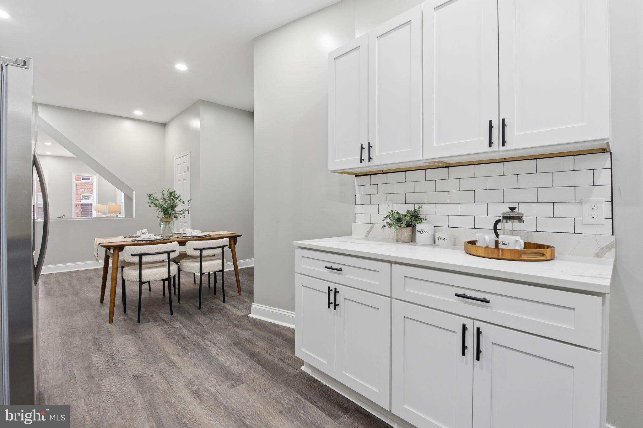 1708 Federal Street Baltimore, MD 21213 - Photo 10 of 33 a kitchen with a table chairs white cabinets and stainless steel appliances
