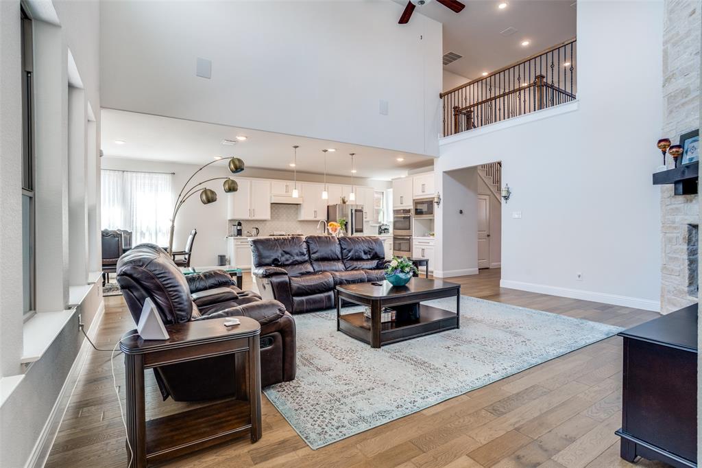 16380 Radstock Road Frisco, TX 75033 - Photo 3 of 39 Living room featuring light wood-type flooring, ceiling fan, a fireplace, recessed lighting, and a high ceiling