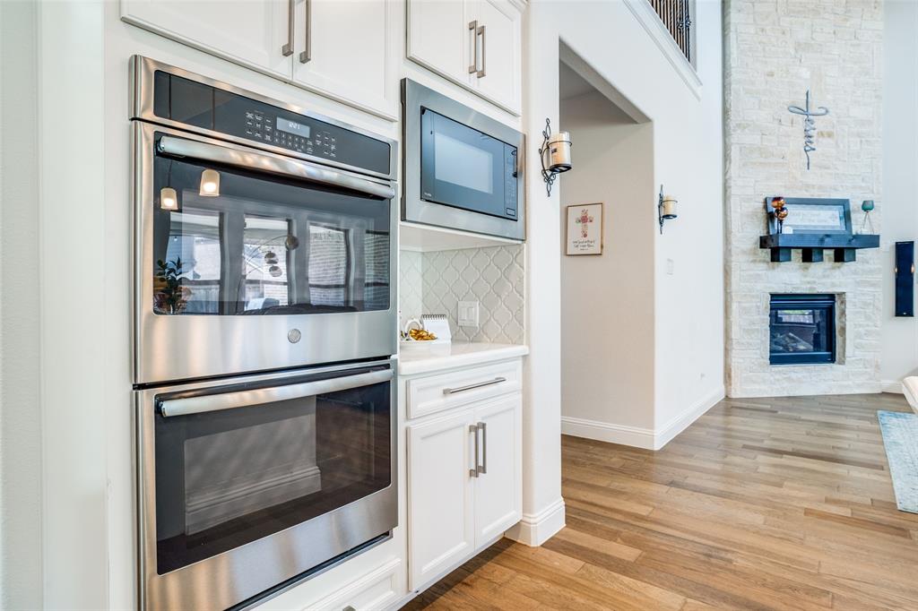 16380 Radstock Road Frisco, TX 75033 - Photo 5 of 39 Kitchen with a fireplace, stainless steel appliances, white cabinets, and light wood-style flooring