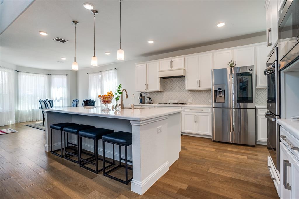 16380 Radstock Road Frisco, TX 75033 - Photo 6 of 39 Kitchen featuring stainless steel appliances, a breakfast bar area, an island with sink, and white cabinets