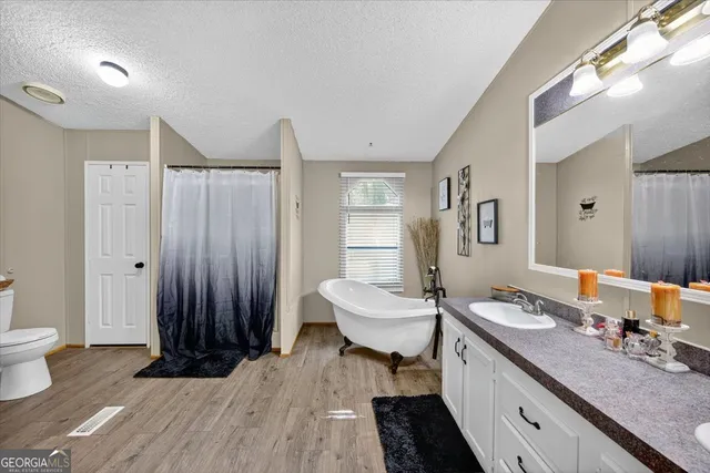 a spacious bathroom with a double vanity sink a mirror and a toilet