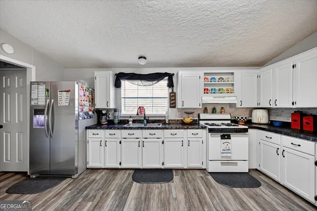 a kitchen with granite countertop a sink cabinets stainless steel appliances and a window