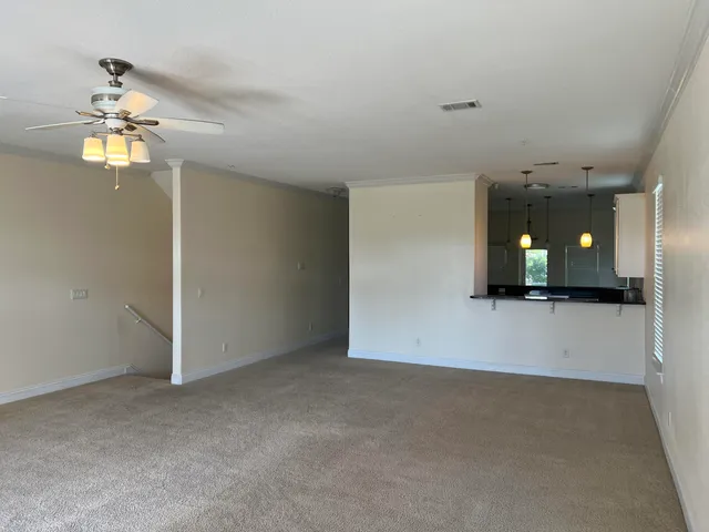 a view of a room with a chandelier fan and wooden floor