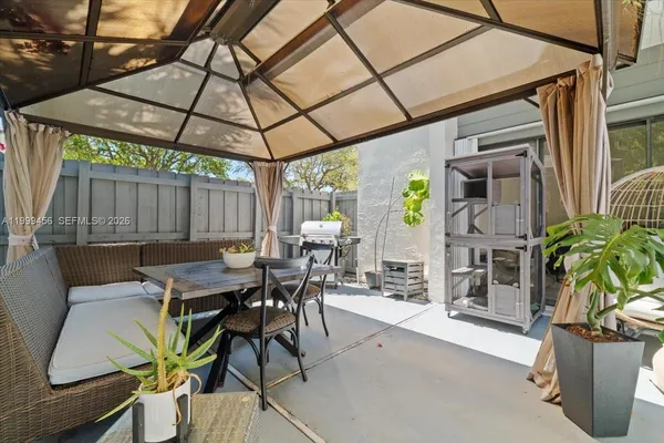 a view of a patio with table and chairs potted plants and large tree