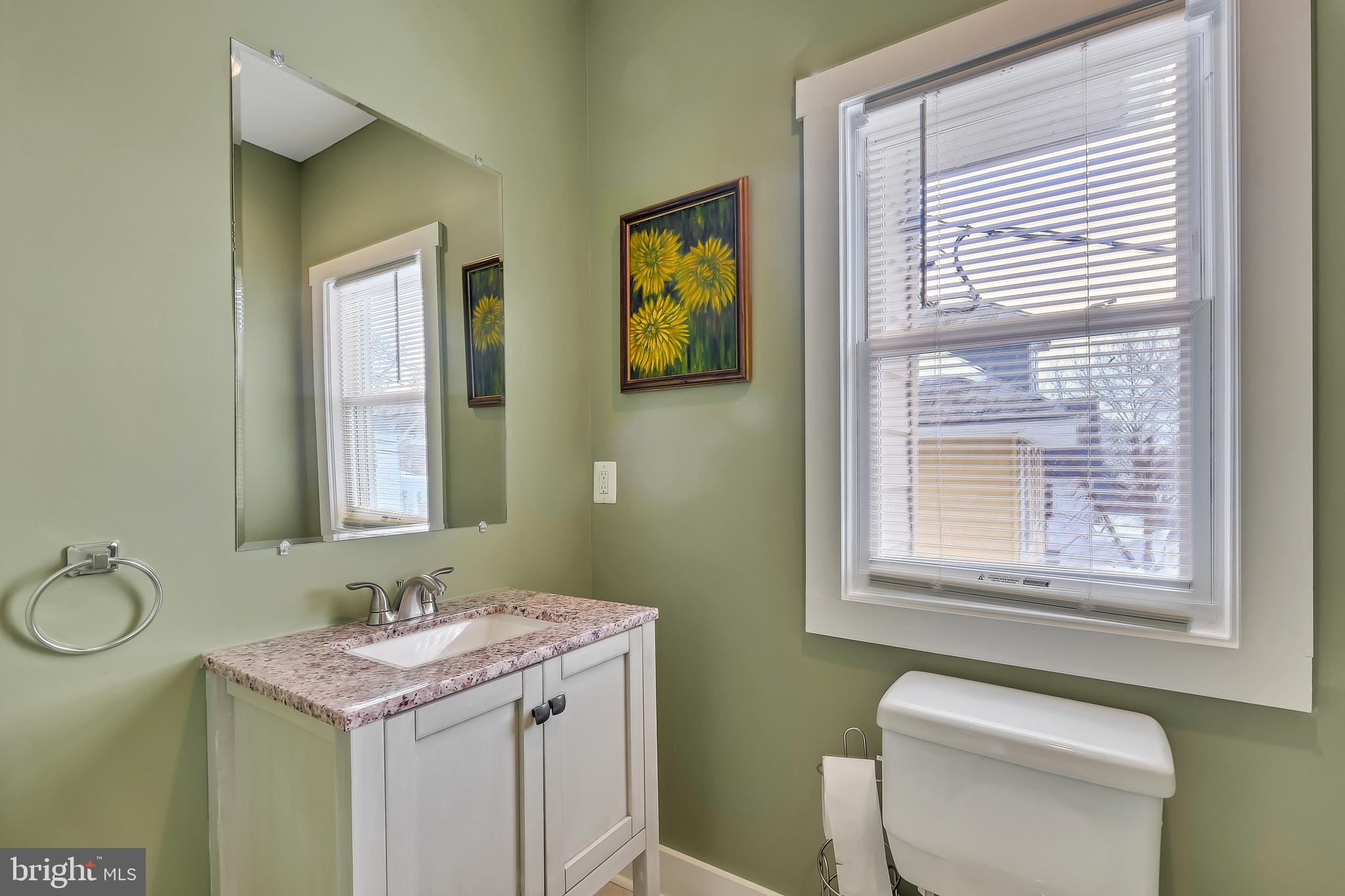3504 Edgewood Road Baltimore, MD 21215 - Photo 41 of 60 a bathroom with a granite countertop toilet a sink and a window
