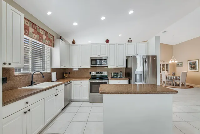 a large kitchen with stainless steel appliances lots of white cabinets