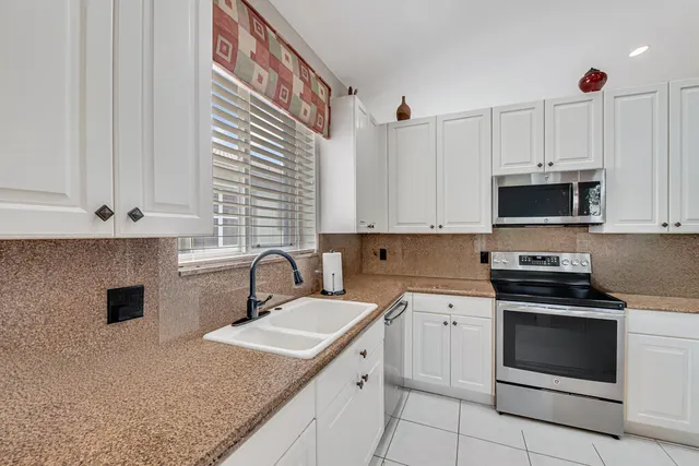a kitchen with granite countertop a sink stainless steel appliances and white cabinets
