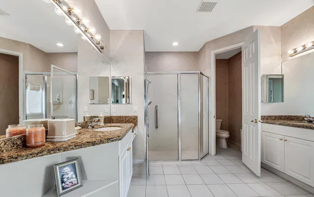 a bathroom with a granite countertop sink a mirror and a refrigerator