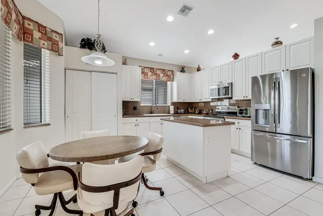 a kitchen with stainless steel appliances kitchen island granite countertop a table chairs stove and microwave