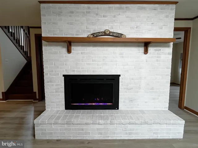 an empty room with wooden floor fireplace and windows