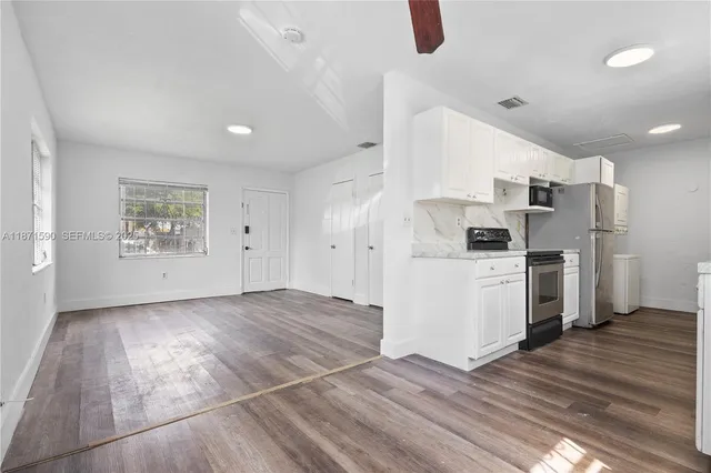 a view of kitchen appliances wooden floor and cabinets