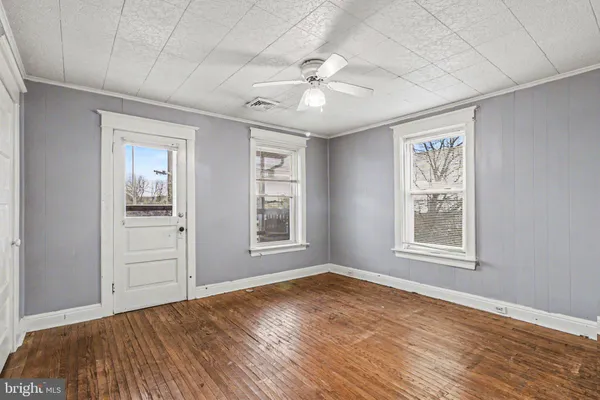 an empty room with wooden floor chandelier and windows