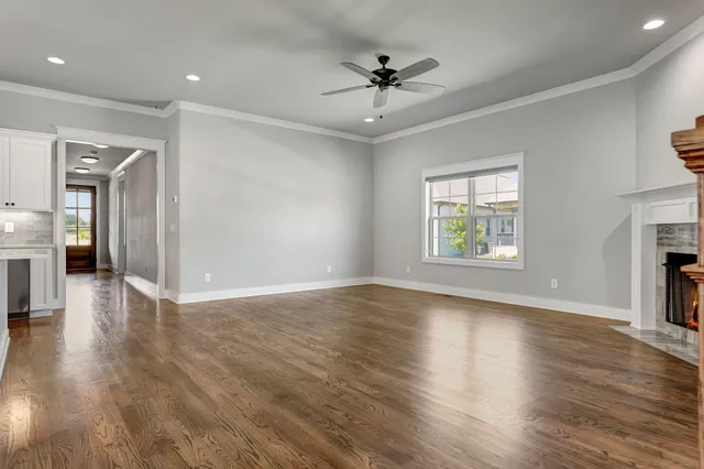 an empty space with wooden floor a ceiling fan and windows