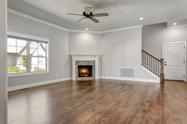 an empty room with wooden floor fireplace and windows