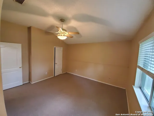 an empty room with windows and fan