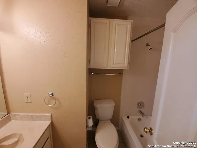 a bathroom with a granite countertop toilet and a sink
