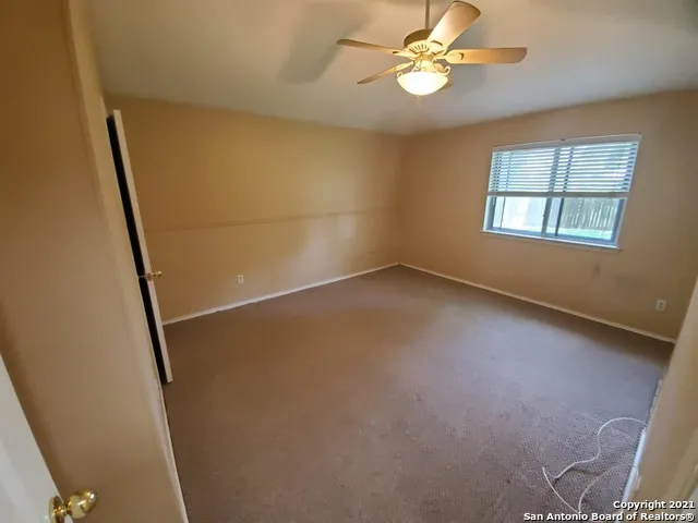 an empty room with windows and fan