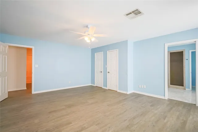 a view of an empty room with chandelier fan