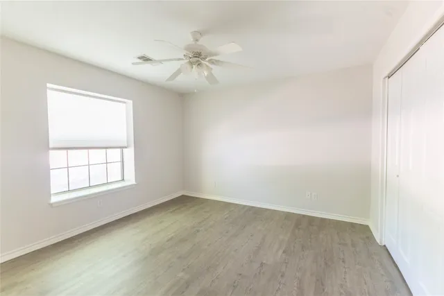 an empty room with windows and fan