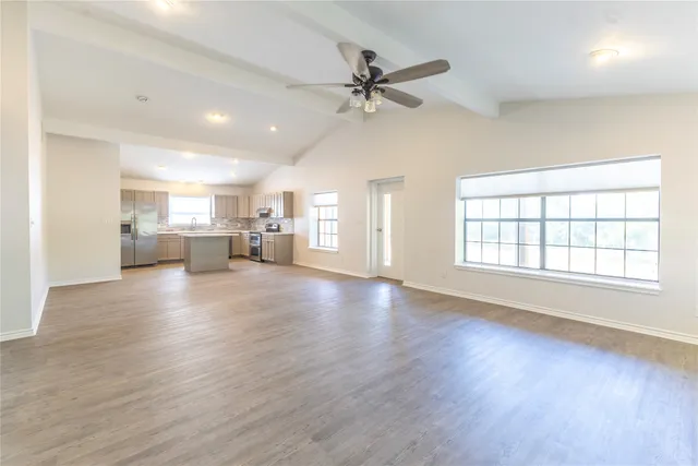 a view of an empty room with a window and wooden floor