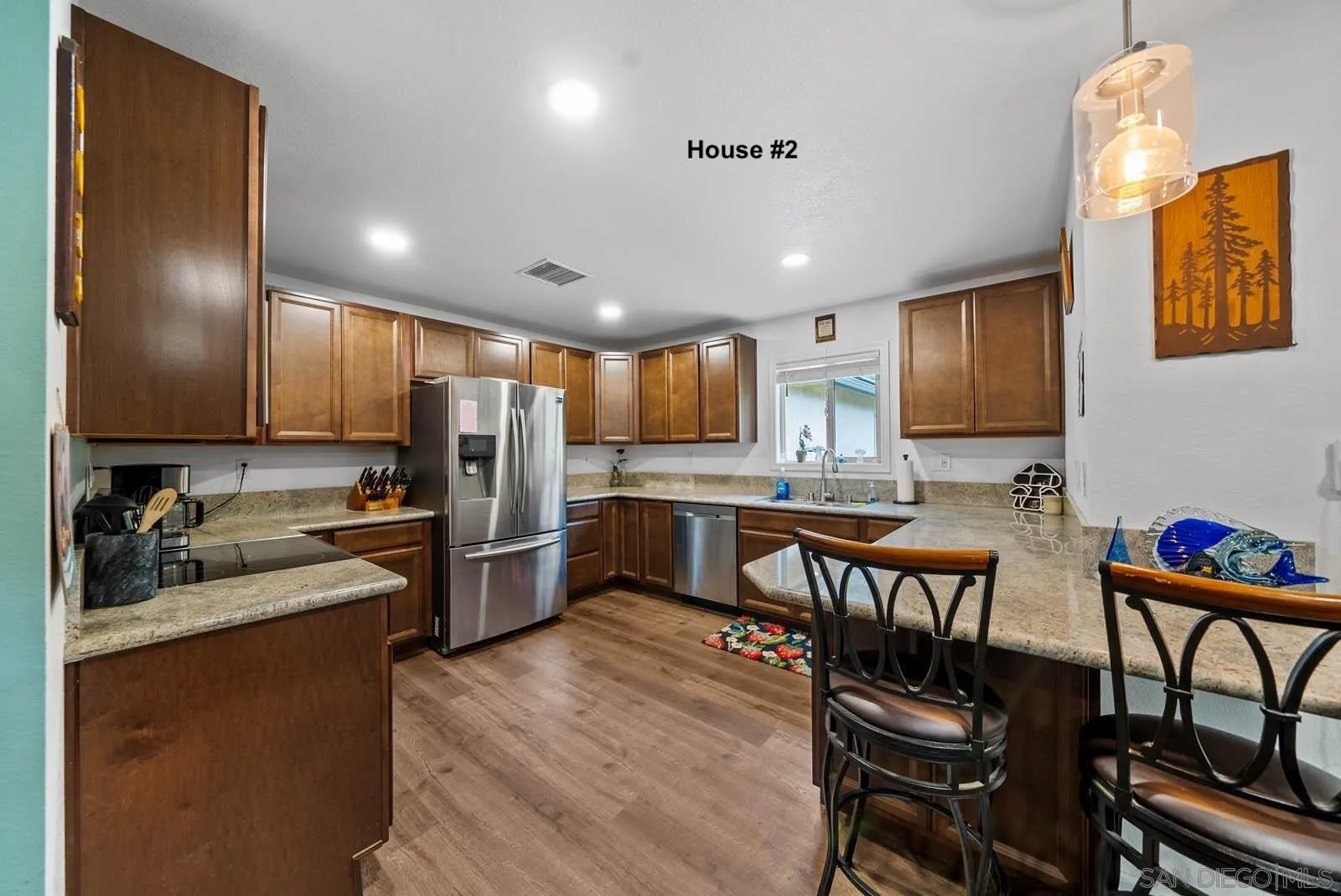 21908 Japatul Lane Alpine, CA 91901 - Photo 24 of 47 a kitchen with stainless steel appliances kitchen island granite countertop a refrigerator a stove a sink a dining table and chairs with wooden floor