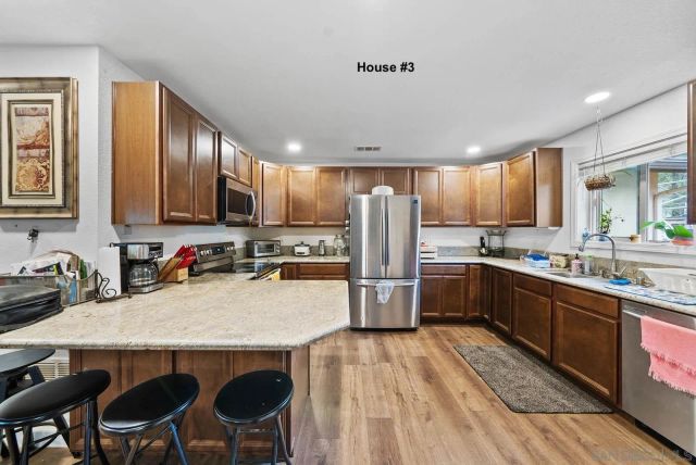 a kitchen with stainless steel appliances granite countertop a sink dishwasher a stove a refrigerator with island and chairs