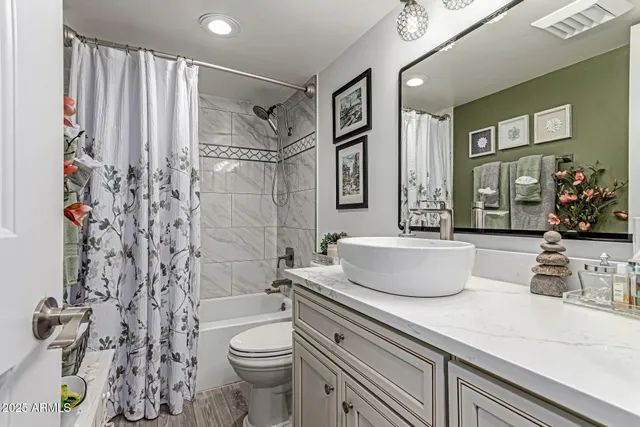 a bathroom with a granite countertop sink a toilet and shower