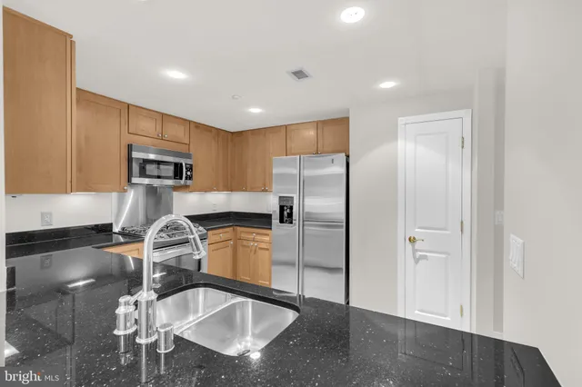 a kitchen with stainless steel appliances granite countertop a sink refrigerator and microwave
