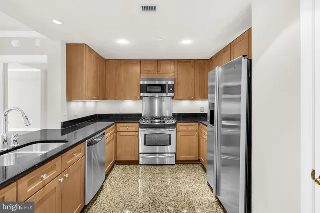 a kitchen with stainless steel appliances granite countertop a refrigerator sink and stove